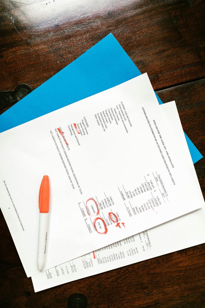 Vista aérea de documentos financieros con secciones resaltadas en rojo en un escritorio de madera.